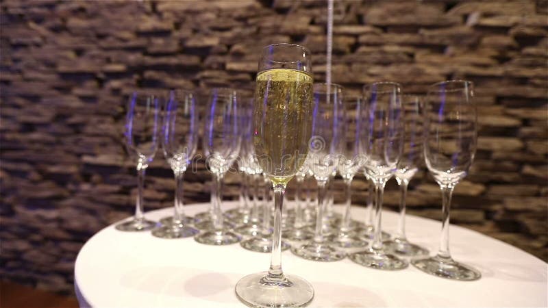 Стекло шампанского на предпосылке пустых стекел, на таблице шведского стола, пена в стекле, движение Шампани камеры